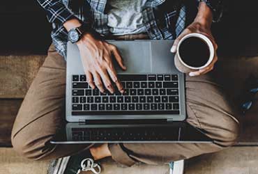 a person with a laptop holding a cup of coffee